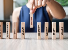 businesswoman hand placing or pulling wooden dominoes with brand text and marketing
