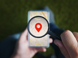 shot of male hands holding magnifying glass with the red icon of geo location and looking