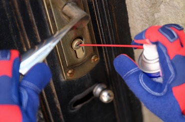 handyman in gloves pouring penetrating lubricant into door lock picture