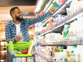 black male shopping groceries in supermarket taking product from shelf