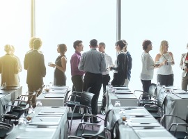 group of people standing by windows of conference room socializing during coffee break