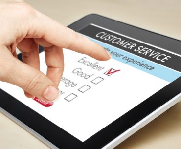 A closeup of a hand using a tablet to fill out a customer service survey.
