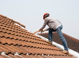 man with caulk gun on roof applying sealant