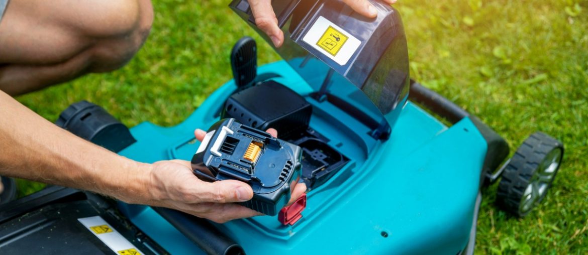 man putting battery into electric cordless lawn mower picture
