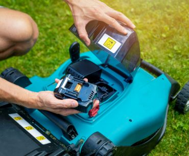 man putting battery into electric cordless lawn mower picture