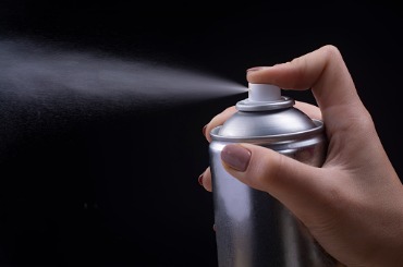 female hand holds an aerosol can on a black background picture