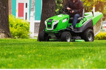 gardener ride on a lawn mowing tractor drives and mows a lawn with picture