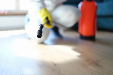man in protective suit treating floor in apartment with disinfectant picture