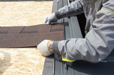 professional worker lays asphalt tile sheet on the roof picture