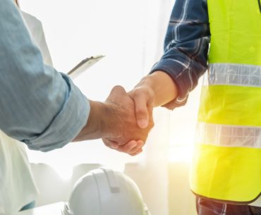 contractor construction worker team hands shaking after plan project picture
