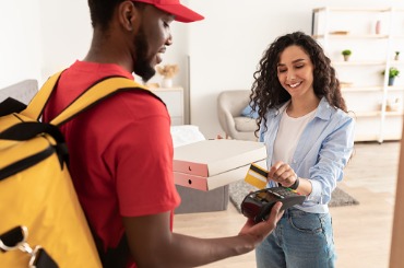 smiling deliveryman holding pos machine woman paying with card picture