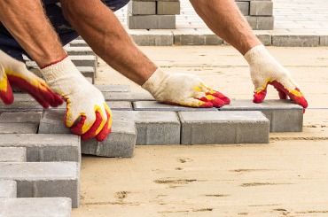 workers lay paving tiles construction of brick pavement close up picture