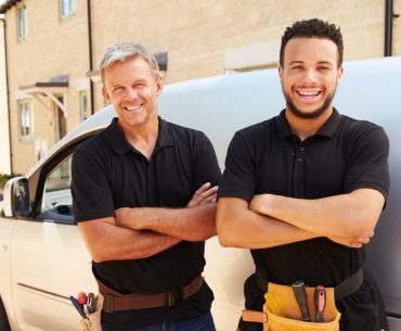 young and a middle aged tradesman by their van