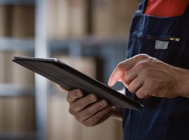 close up on a mans hands using digital tablet computer while standing in the warehouse