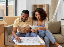 couple with blueprint counting money at home