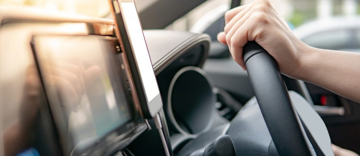 male driver hand holding on steering wheel using smartphone for gps navigation mobile phone