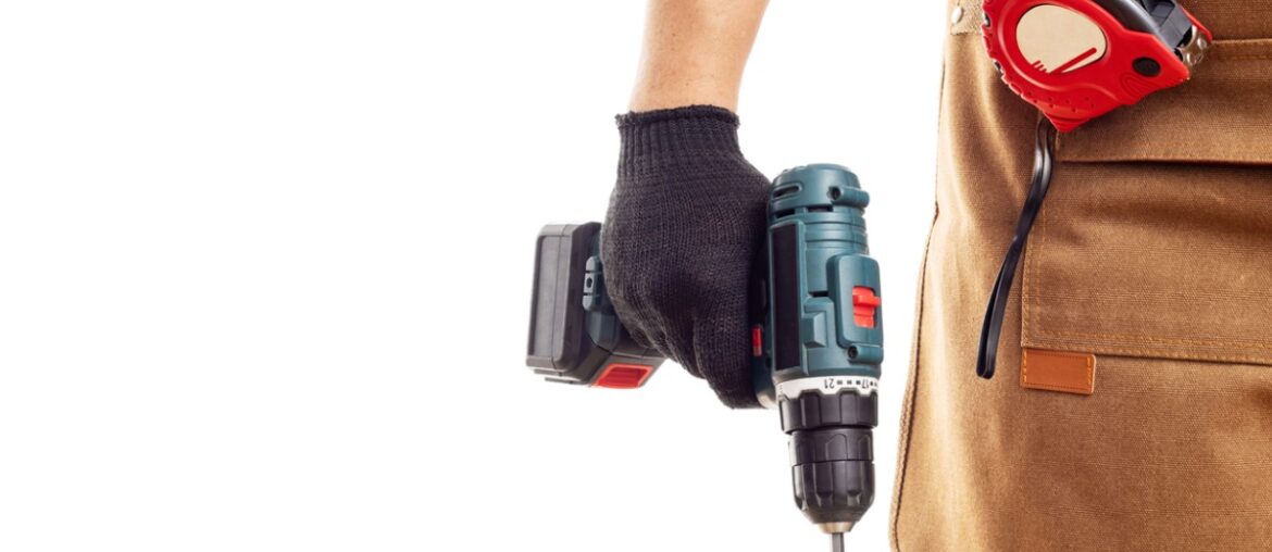 man-in-apron-and-gloves holds cordless screwdriver on white background